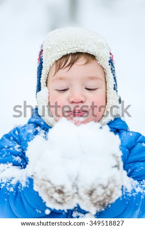 Happy child blowing snow in winter park