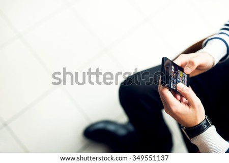 Hands holding mobile phone. Checking some information about sold photos at stock market. Shallow depth of field and selective focus on bottom of the smart phone.