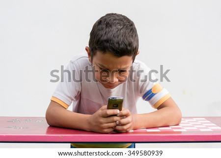 Bullied sad gypsy child boy calling home with mobile phone from school for help Royalty-Free Stock Photo #349580939