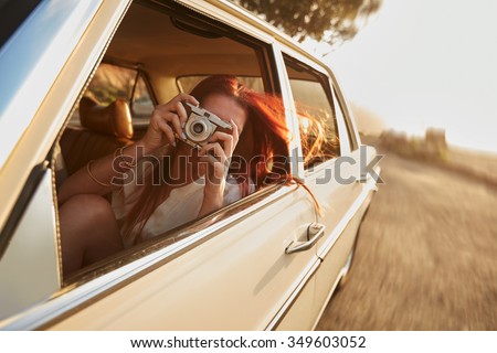 Shot of  young woman taking photos while sitting in a car. Female capturing a perfect road trip moment. Royalty-Free Stock Photo #349603052