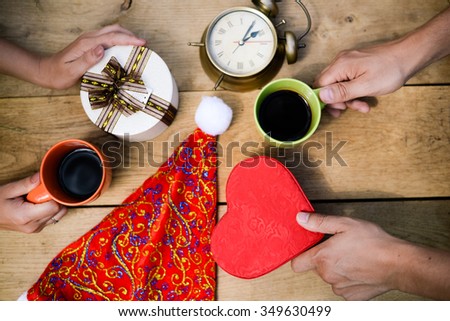 Picture of male and female hands with giftboxes and cups of coffee. Closeup of romantic arrangement on wooden plank background.