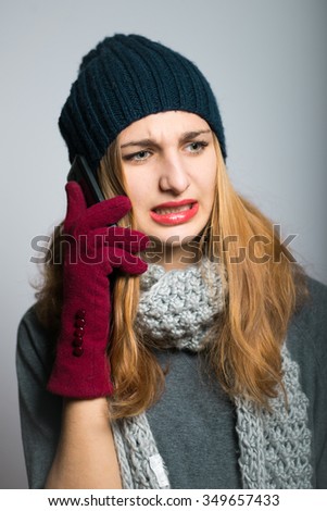 blonde girl angrily talking on the phone, Christmas concept, studio photo isolated on a gray background