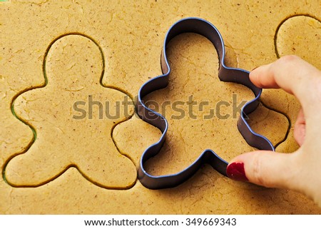 Female hand making christmas gingerbread men cookies with metal cutter