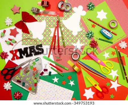Arts and craft supplies for Christmas. Red and green color paper, pencils, different washi tapes, craft scissors, cardboard cuts, festive Xmas supplies for decoration.