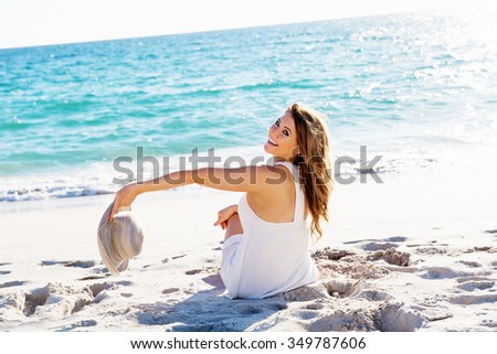 Portrait of young pretty woman with hat sitting on the beach