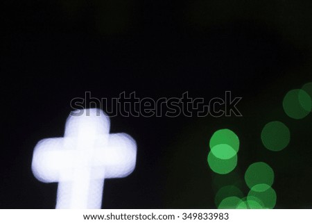 white cross with green bokeh in the dark night