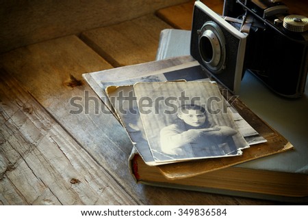 old photo camera, antique photos and old book on wooden table. selective focus
