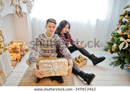 Young stylish couple with Christmas gifts and New Year decoration. Soft warm color tone.