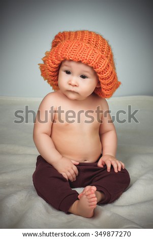 Little girl in a funny hat on a gray background