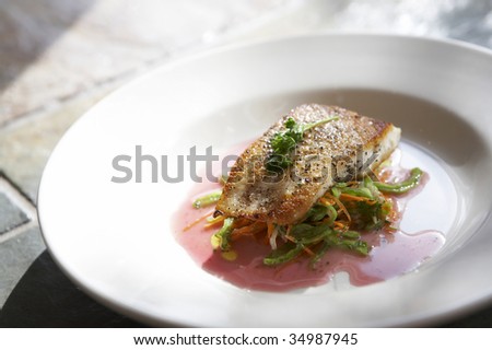 Fish fillet over vegetables on a white plate elegantly styled