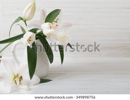 lily in jug on white wooden background