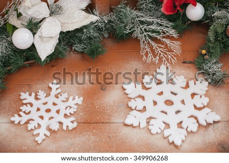 Christmas background with green pine branch, snowflakes and white baubles on wooden board. Background with snowflakes on wooden table with copy space