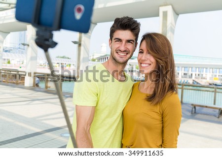 Caucasian couple take photo by cellphone stick