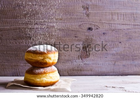 Donut in powdered sugar on a wooden background in rustic style. Selective focus.
