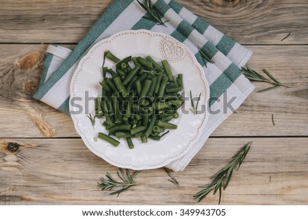 Delicious fresh green beans with rosemary decoration on the wooden table background