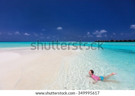 Little girl on vacation swimming in a shallow water at tropical lagoon