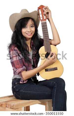 Portrait of smiling country girl sitting on a wooden chair with her small acoustic guitar, isolated on white background