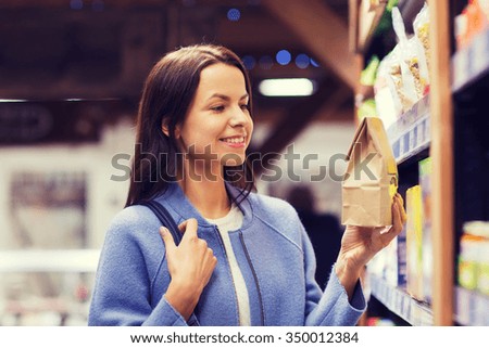 sale, shopping, consumerism and people concept - happy young woman choosing and buying food in market