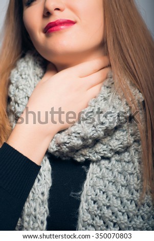 bright beautiful girl has caught a cold and sore throat, Christmas and New Year concept, studio photo isolated on a gray background