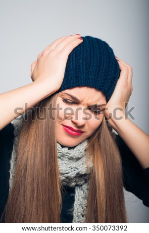 bright beautiful girl has a severe headache, Christmas and New Year concept, studio photo isolated on a gray background