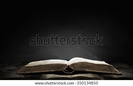 Opened book with light on pages on black background