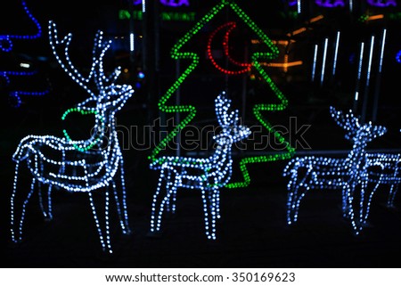 Blurred bokeh light background of decorated glowing Christmas tree and deer