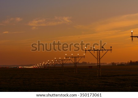 Picture taken of the runway during a colorful sunset sky.