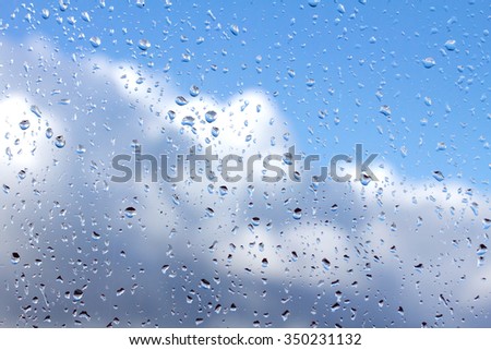rain drops on glass with blue sky white clouds