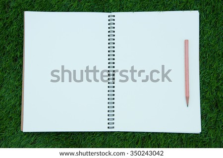 book and pencil with grass background