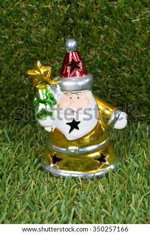 A doll of Santa Claus  with christmas decoration on green grass