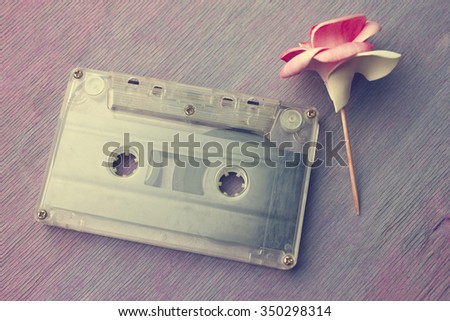 rose and vintage audio cassette on a wooden background