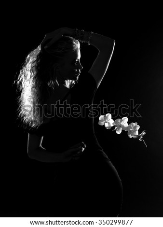 Silhouette curly blonde with a good figure in a black dress on a black background with royal orchid