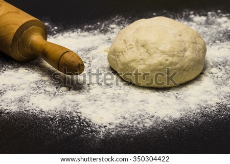 Dough with rolling pin and flour on a stone surface
