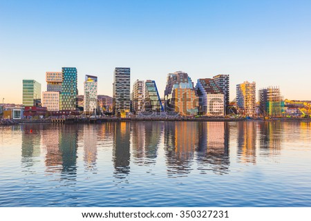 Modern buildings in Oslo, Norway, with their reflection into the water. These are some of the new buildings in the neighbourhood of Bjorvika. Concepts of travel and architecture. Royalty-Free Stock Photo #350327231