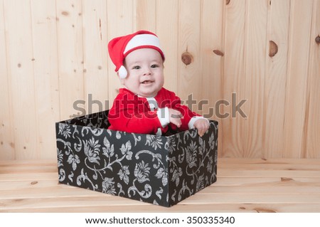 young baby wearing a santa claus suit and hat in christmas in a barn