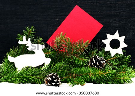 Christmas card with Christmas tree decorations and a fir tree branch on a thread. An empty card for an inscription and bright Christmas balls on a wooden black background