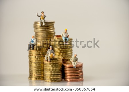 Construction workers sitting on money coin piles. Macro photo