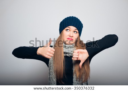 bright girl doubts in choosing winter concept studio photo isolated on a gray background