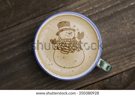 Cup of coffee latte art on wood table. Foam form of snowman.