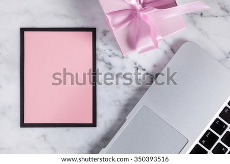 Greeting card with space for text, gift and laptop are on the marble table