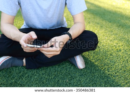 man sitting use smartphone on artificial turf