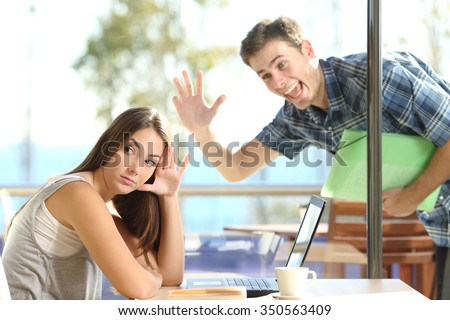 Girl ignoring and rejecting to a stalker man waving her in a coffee shop in a blind date Royalty-Free Stock Photo #350563409