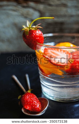 Lemonade with fresh strawberries and lemon . Rustic background