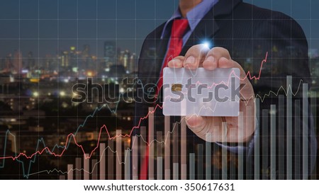 businessman holding smart card and visual graph on screen with night city background