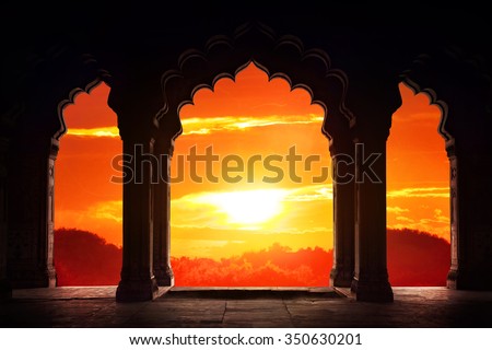Indian arch silhouette in old temple at dramatic orange sunset sky background. Free space for text