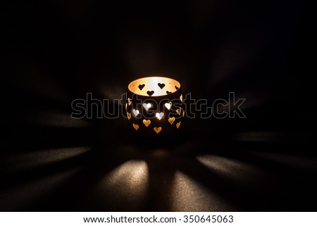 Burning candle. Black background. Heart silhouette
