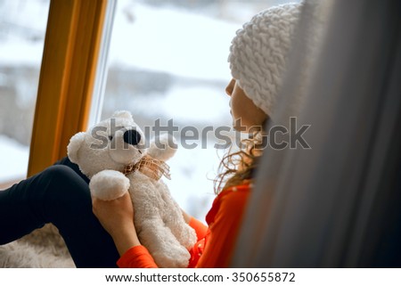 Cute girl with long hair sitting alone near window