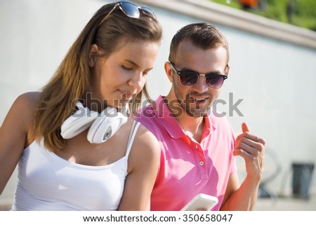 Young smiling couple in summer street using smartphone