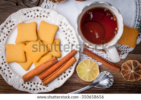 Hot tea with citrus, cinnamon, cloves and honey on a wooden table.