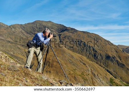 Professional photographer making landscape photos by digital mirror camera and tripod at rock mountainon